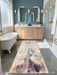 2.8' x 8' runner beige & blue abstract watercolor modern area rug placed in a bright bathroom with dual vanities and a freestanding tub.