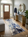 2.8' x 8' runner ivory & blue abstract watercolor modern area rug placed in a bright entryway with a wooden console table and round mirror.