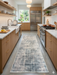 2.8' x 8' runner ivory & blue distressed linear modern area rug placed in a bright kitchen with light wood cabinetry and stainless steel appliances.