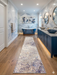 2.8' x 8' runner ivory gray & blue marble swirl abstract modern area rug placed in a bathroom with marble walls, double vanity, and a freestanding tub.