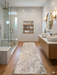 2.8' x 8' runner ivory & gray marble swirl abstract modern area rug placed in a bathroom with marble tile, double vanity, and warm wood accents.