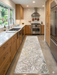 2.8' x 8' runner ivory & gray marble swirl abstract modern area rug placed in a bright kitchen with wood cabinetry, stainless appliances, and clean white surfaces.