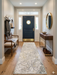 2.8' x 8' runner ivory & gray marble swirl abstract modern area rug styled in an entryway with a dark front door, console table, and minimal decor.