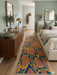 2.8' x 8' runner multicolor terracotta & blue abstract organic geometric modern area rug placed beside a bed in a cozy bedroom with soft neutral bedding and wood furniture.