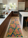 2.8' x 8' runner multicolor terracotta & blue abstract organic geometric modern area rug placed in a bright kitchen with wood cabinetry, white countertops, and light wood flooring.