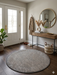 3' Round Taupe Gray Distressed Minimalist Modern Washable Area Rug placed in an entryway with a console table, round mirror, and neutral decor.