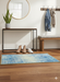 2' x 3' Rectangular Blue Abstract Washable Area Rug placed in a modern entryway with a sleek console table, coat hooks, and warm wooden floors.