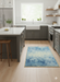 2' x 3' Rectangular Blue & Light Blue Abstract Modern Washable Area Rug placed in a contemporary kitchen with gray cabinets and light wood flooring.