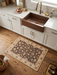 2' x 3' Rectangular Brown & Ivory Floral Traditional Washable Area Rug styled in a bright farmhouse kitchen in front of a copper sink.