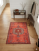 2' x 3' Rectangular Coral Red Tribal Medallion Traditional Washable Area Rug placed in an entryway with a console table, bench, and natural wood flooring.