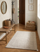 2' x 3' Rectangular Ivory & Beige Distressed Abstract Modern Washable Area Rug styled in a welcoming entryway beside a wooden bench.