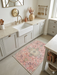 2' x 3' Rectangular Pink Ivory Distressed Medallion Vintage Traditional Area Rug styled in a kitchen.