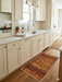2' x 3' Rectangular Rust Gold Distressed Abstract Modern Washable Area Rug styled in a bright kitchen with cream cabinetry, white countertops, and warm wood flooring.