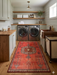 2' x 4' Runner Coral Red Tribal Medallion Traditional Washable Area Rug placed in a laundry room with front-load washers, wood countertops, and open shelving.