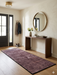 2' x 5' rectangular brown & rust geometric minimalist modern area rug styled in an entryway with a wooden console table and round mirror.