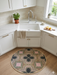 3' Round Pink Green Geometric Bohemian Washable Area Rug styled in a bright kitchen beneath a farmhouse sink with white cabinetry and warm wood flooring.