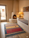 3' x 5' Rectangular Gold & Red Geometric Southwestern Area Rug styled in a rustic hallway with a corner fireplace.