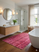 3' x 5' Rectangular Rose Pink & Burgundy Distressed Vintage Area Rug styled in a bathroom with modern fixtures and natural light.