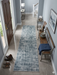 3' x 8' Runner Blue Gray Grid Modern Washable Area Rug displayed in a bright entryway with polished tile floors, light blue walls, and transitional furnishings.