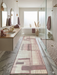 3' x 8' Runner Blush Pink Abstract Geometric Modern Washable Area Rug placed in a spa-inspired bathroom with marble floors, a freestanding tub, and soft pink accents.