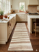 3' x 8' Runner Ivory & Blush Striped Modern Washable Area Rug styled in a warm contemporary kitchen with cream cabinetry, marble countertops, and natural wood flooring.
