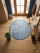 4' Round Blue & Ivory Geometric Minimalist Modern Area Rug styled in an entryway with wood flooring, a bench, and natural light.