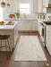 4' x 6' Rectangular Ivory & Gold Distressed Abstract Modern Washable Area Rug placed in a bright modern kitchen between white cabinets.