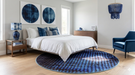 5' Round Blue & Light Blue Abstract Modern Area Rug placed in a contemporary bedroom with blue décor and wood flooring.