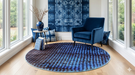 5' Round Blue & Light Blue Abstract Modern Area Rug styled in a bright sunroom seating area with blue accent chair and large windows.