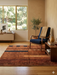 5' x 5' Square Rust & Black Abstract Geometric Modern Area Rug placed in a contemporary living room with warm wood furniture and a navy accent chair.