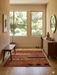 5' x 5' Square Rust & Black Abstract Geometric Modern Area Rug styled in a bright entryway with minimalist decor and natural light.