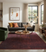 5' x 7' Rectangular Burgundy Red Distressed Solid Modern Washable Area Rug styled in a living room with a gray sofa and mid-century decor.