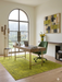 5' x 7' Rectangular Mustard Gold Distressed Medallion Traditional Washable Area Rug styled in a home office with a wooden desk, green swivel chair, and scenic arched window views.
