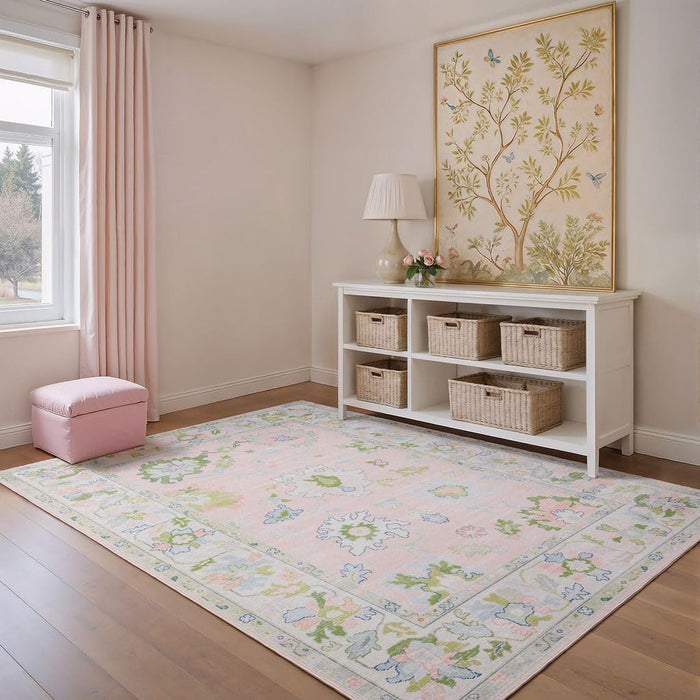 5' x 7' Rectangular Pink Multicolor Floral Traditional Washable Area Rug styled in a soft pastel nursery with white storage shelves, woven baskets, and botanical wall art.