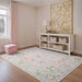 5' x 7' Rectangular Pink Multicolor Floral Traditional Washable Area Rug styled in a soft pastel nursery with white storage shelves, woven baskets, and botanical wall art.