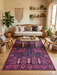 5' x 7' Rectangular Purple & Pink Tribal Southwestern Washable Area Rug placed in a cozy bohemian living room beneath a wooden coffee table.