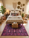 5' x 7' Rectangular Purple & Pink Tribal Southwestern Washable Area Rug styled in a warm boho bedroom under a rustic wooden bed.