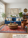 5' x 7' Rectangular Red & Blue Floral Traditional Area Rug placed in a bright living room with blue sofa and round coffee table.