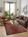 5' x 7' Rectangular Red & Blue Tribal Geometric Medallion Traditional Area Rug styled in a living room with a sofa, accent chair, and coffee table.