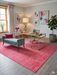 5' x 8' Rectangle Pink Distressed Modern Washable Area Rug styled in a contemporary living room with a neutral sofa, teal accent chair, and glass coffee table.
