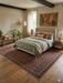 5' x 8' Rectangular Brown & Rust Repeating Medallion Traditional Washable Area Rug styled in a warm bedroom under a neatly made bed.