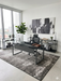 5' x 8' Rectangular Charcoal Ivory Distressed Abstract Modern Area Rug shown in a sleek home office beneath a black desk and ergonomic chair.