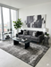 5' x 8' Rectangular Charcoal Ivory Distressed Abstract Modern Area Rug styled in a contemporary living room with a gray sofa, black coffee table, and monochrome wall art.