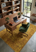 5' x 8' Rectangular Gold & Mustard Distressed Floral Traditional Washable Area Rug styled in a home office with wood shelving and mid-century accents.