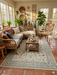 5' x 8' Rectangular Ivory Blue Floral Traditional Oriental Area Rug styled in a sunroom with rattan furniture and plants.