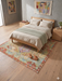 5' x 8' Rectangular Multicolor Distressed Tribal Geometric Vintage Washable Area Rug styled in a bedroom with light wood furniture and soft neutral bedding.