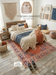 5' x 8' Rectangular Red & Blue Floral Medallion Traditional Persian Washable Area Rug styled in a cozy boho bedroom with wooden bed frame and woven wall décor.
