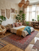 5' x 8' Rectangular Red & Navy Floral Medallion Traditional Area Rug styled in a warm boho bedroom under a low platform bed.