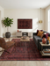 5' x 8' rectangular burgundy & black distressed tribal traditional area rug styled in a living room with a gray sofa, leather chair, and wood accents.