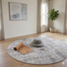 6' Round Beige & Gray Distressed Abstract Modern Area Rug styled in a minimal space with light wood flooring and neutral decor.